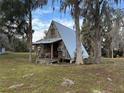 A-frame cabin with metal roof, wooden porch, and surrounding trees at 668 County Road 485, Lake Panasoffkee, FL 33538