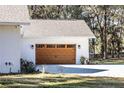 Attached garage with a wooden door and exterior lighting at 871 Cr 548, Bushnell, FL 33513