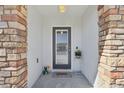 Inviting front porch with decorative stone pillars, a charming doormat, and potted plants enhancing the home's curb appeal at 12306 Ne 48Th Way, Oxford, FL 34484
