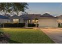 House exterior at dusk, two-car garage, and landscaping at 17030 Se 79Th Clearview Ave, The Villages, FL 32162