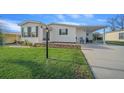 Single-wide manufactured home with carport and landscaped lawn at 1706 Pebble Beach Ln, Lady Lake, FL 32159