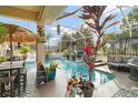 Relaxing screened pool area with patio furniture and tropical plants at 17430 Se 115Th Terrace Rd, Summerfield, FL 34491