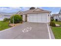 A decorative driveway leads to a tan house with a garage at 2240 Avon Loop, The Villages, FL 32162