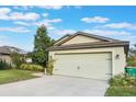 Landscaped front yard and light green house exterior with a two-car garage at 2334 Bexley Dr, Tavares, FL 32778