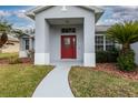 Red front door entryway with a walkway and landscaping at 27302 Orchid Glade St, Leesburg, FL 34748