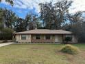 Tan one-story house with brown roof, stone accents, and a covered porch at 403 W Palm Ave, Bushnell, FL 33513