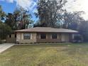 Tan one-story house with brown roof, stone accents, and a covered porch at 403 W Palm Ave, Bushnell, FL 33513