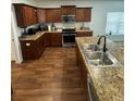 Well-lit kitchen featuring wood cabinets, granite countertops, stainless steel appliances, and hardwood floors at 4556 Water Oak Ter, Oxford, FL 34484