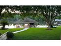 Scenic backyard view featuring a covered boat dock on the water with green lawn and mature trees at 6216 Landings Blvd, Lady Lake, FL 32159