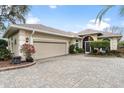 Single-story home features a manicured lawn, mature landscaping, and a brick driveway leading to an attached garage at 6216 Landings Blvd, Lady Lake, FL 32159