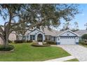 One-story house with a large tree in the front yard, and paver driveway at 9033 Laurel Ridge Dr, Mount Dora, FL 32757