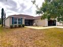 Tan exterior house with green shutters and a spacious yard at 9616 Se 168Th Elderberry Pl, The Villages, FL 32162