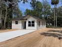 Exterior view of a newly built home with fresh concrete driveway surrounded by natural vegetation at Lot 42 Indian Estates Cr 423, Lake Panasoffkee, FL 33538