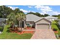 Single-story home with a landscaped yard and paver driveway at 10377 Silver Maple Ave, Oxford, FL 34484