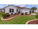 Side view of a white house showcasing the landscaping and a partial view of the driveway at 1216 Addison Ave, The Villages, FL 32162