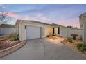 Evening view of a yellow house with a white garage door and walkway at 1410 Conchas Dr, The Villages, FL 32162