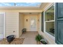 Front entry with white door, wood bench and small plants at 1410 Conchas Dr, The Villages, FL 32162