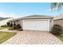 Two-car garage with white doors and paver driveway at 1548 Loris Loop, The Villages, FL 32162