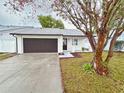 Newly renovated home with white exterior, brown garage door, and landscaped yard at 1562 Lawndale Cir, Winter Park, FL 32792