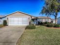 Front view of a tan house with garage and landscaping at 2009 Claudio Ln, The Villages, FL 32159