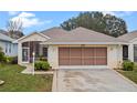 Front view of a single story house with a two-car garage at 21122 Lionheart Dr, Leesburg, FL 34748