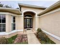 Front entrance with arched entryway and decorative glass door at 33304 Kaylee Way, Leesburg, FL 34788