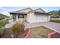 House exterior showcasing a 2-car garage and paved driveway at 392 Arbella Loop, The Villages, FL 32162