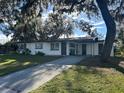 Front view of a ranch home with a driveway and large oak trees at 609 Scenic St, Leesburg, FL 34748