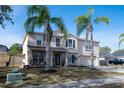 Two-story house with tan exterior, two-car garage, and palm trees at 702 Skyridge Rd, Clermont, FL 34711