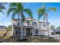 Two-story house with tan exterior, two-car garage, and palm trees at 702 Skyridge Rd, Clermont, FL 34711