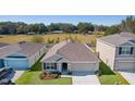 One-story house with a two-car garage and landscaping, wider aerial view at 8661 Triumph Cir, Wildwood, FL 34785