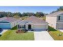 One-story house with a two-car garage and landscaping, wider aerial view at 8661 Triumph Cir, Wildwood, FL 34785