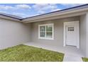 White front door and window with covered porch and grassy area at 1 Malauka Pass Ct, Ocklawaha, FL 32179