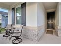 Inviting front porch with stylish chairs, textured stone accents, and a modern black front door at 10161 Spring Lake Dr, Clermont, FL 34711