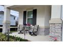 Front porch with stone columns, two chairs, and flowering plants at 10161 Spring Lake Dr, Clermont, FL 34711