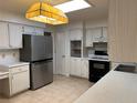 Bright kitchen with a stainless steel refrigerator, white cabinets, and modern lighting at 1511 Spanish Ave, Leesburg, FL 34748