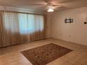 Open living room featuring tile flooring, a ceiling fan, and a large window with curtains at 1511 Spanish Ave, Leesburg, FL 34748