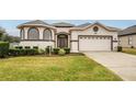 House exterior showcasing a two-car garage and attractive landscaping at 16904 Se 110Th Court Rd, Summerfield, FL 34491