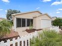 Tan exterior house with a white picket fence and landscaping at 16958 Se 94Th Sunnybrook Cir, The Villages, FL 32162