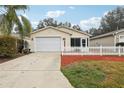 Front view of a tan house with a white picket fence and a two-car garage at 17461 Se 93Rd Retford Ter, The Villages, FL 32162