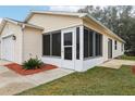 Side view of a tan house with a screened porch and landscaping at 17461 Se 93Rd Retford Ter, The Villages, FL 32162