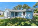 Side view of a light blue house with a screened porch and lush green lawn at 26548 Deuce Ct, Leesburg, FL 34748