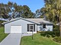 House with a white garage door, driveway and green lawn at 26548 Deuce Ct, Leesburg, FL 34748