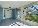 Covered front porch with a white door and a view of the backyard at 26548 Deuce Ct, Leesburg, FL 34748