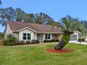 Tan one story house with brown roof, landscaping, and screened garage at 26913 Racquet Cir, Leesburg, FL 34748