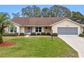 Tan one-story house with brown roof, landscaping, and screened garage at 26913 Racquet Cir, Leesburg, FL 34748