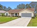 Tan one-story house with brown roof and screened garage at 26913 Racquet Cir, Leesburg, FL 34748