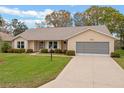 Charming single-story home with a well-maintained lawn, landscaped shrubs, and a two-car garage at 26913 Racquet Cir, Leesburg, FL 34748