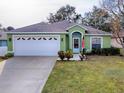 Green house with white garage door and landscaping at 30111 Pga Dr, Mount Plymouth, FL 32776