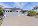 Gray three-car garage home with landscaped yard and palm trees at 4923 Lawler Loop, The Villages, FL 32163